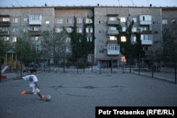 A boy plays soccer in a courtyard in Ulken.