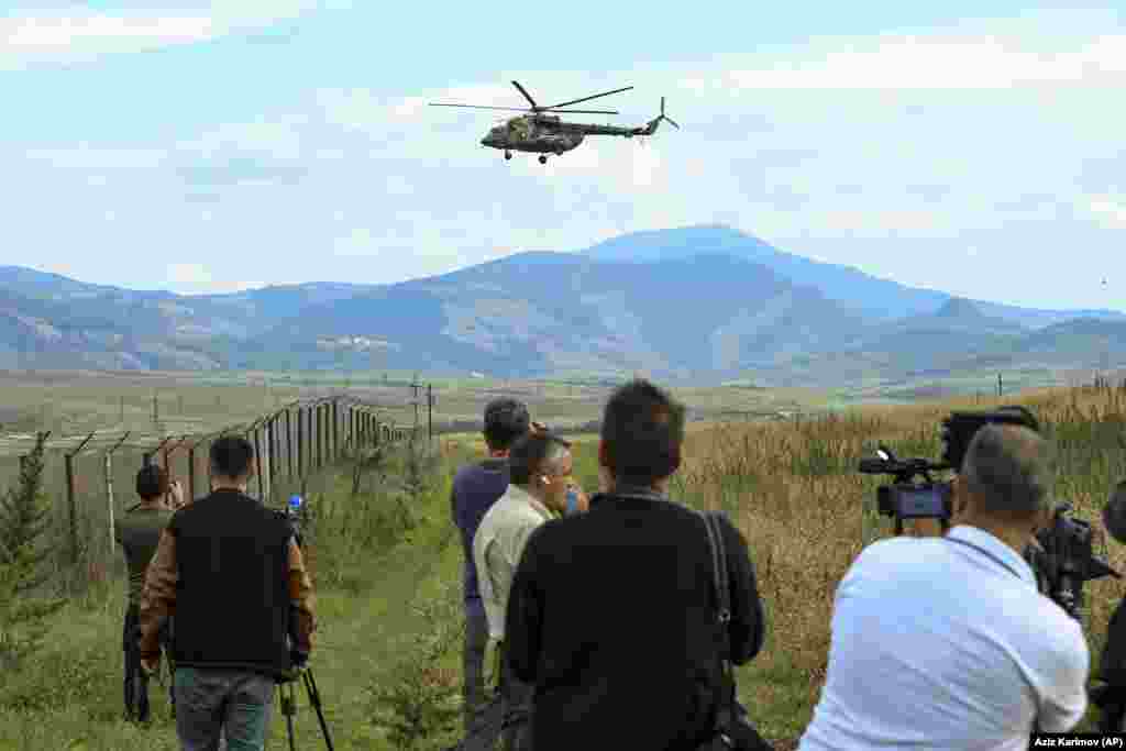An international group of journalists film a Russian peacekeepers' military helicopter as it flies over a field just outside Xankendi on October 2. Armenian authorities have accused the Russian peacekeepers who were deployed to Nagorno-Karabakh after the 2020 war of standing by and failing to stop the Azerbaijani onslaught. Moscow has rejected the accusations, arguing that its troops did not have a mandate to intervene.