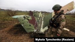 Український військовий сапер оглядає уламки російського бойового літака Су-25, збитого ЗСУ на Київщині, 21 квітня 2022 року