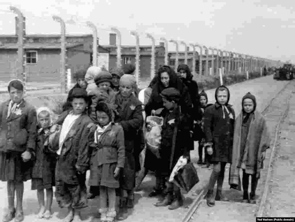 На фото слева: 1944 год. Женщина с детьми направляется в газовую камеру. На заднем фоне видны деревянные бараки &ndash; это лагеря Биркенау, дополнительно построенные в Освенциме. После войны здания были разрушены, но кирпичные стены и дымоходы сохранились.