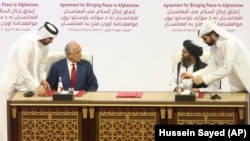 U.S. peace envoy Zalmay Khalilzad (left) and Mullah Abdul Ghani Baradar, the Taliban's top political leader, sign a historic peace agreement between Taliban and U.S. officials in Doha on February 29.